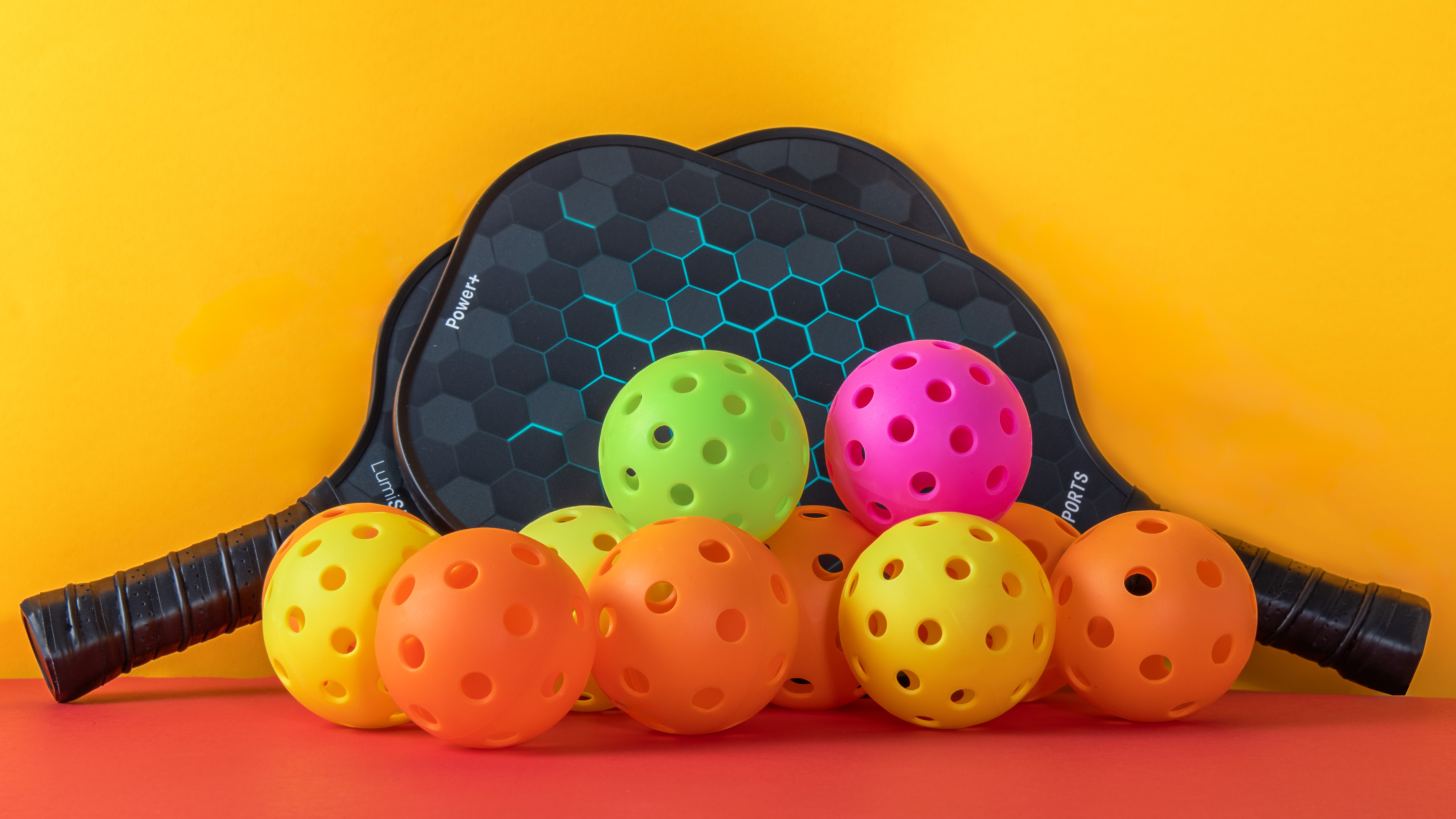 Pickleball kit on non-white background - shot in studio pickleball paddles and balls on yellow and orange background shot in studio